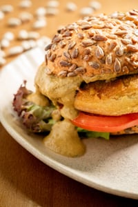 Burger végétarien aux pois chiches et haricots, garni d'un mélange croustillant de graines et de fruits secs. À l'intérieur,
