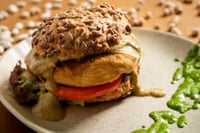 Burger végétarien aux pois chiches et haricots, servi au restaurant MATRICE, avec un pain complet parsemé de graines et
