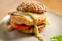 Hamburguesa vegetal de garbanzos y alubias servida en el restaurante MATRICE, con pan integral cubierto de semillas y