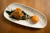 A gourmet dish of venison meatballs served at MATRICE Restaurant, accompanied by fresh spinach, toasted grains, and a touch