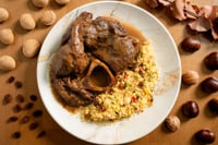 Plato de ossobuco de ternera servido sobre un lecho de couscous, bañado en una salsa oscura y aromática. La composición